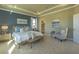 Beautifully staged bedroom with a tray ceiling, an upholstered chair, and an ensuite bathroom at 14466 Pioneer Ridge Dr, Hudson, FL 34667