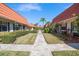 A well-manicured community with paved walkways, green lawns, mature palm trees, and red tile roofs at 19029 Us Highway 19 N # 19C, Clearwater, FL 33764