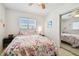 Bright bedroom with colorful floral bedding, ceiling fan and sliding mirror closet doors at 214 Driftwood N Dr, Palm Harbor, FL 34683