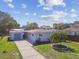 An inviting single-story home features a well-manicured lawn and a blue garage door at 214 Driftwood N Dr, Palm Harbor, FL 34683