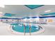 Bright and spacious indoor swimming pool with blue accents, tile flooring and ladder at 2218 Mayfield Palms Ln # 323, Sun City Center, FL 33573