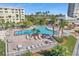 An aerial view showcases a pool with lounge chairs, umbrellas, palm trees, and manicured landscaping at 4775 Cove Cir # 205, St Petersburg, FL 33708