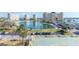Expansive view of complex featuring a tranquil pond, palm trees, parking, and pristine landscaping at 4775 Cove Cir # 205, St Petersburg, FL 33708