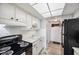 Cozy kitchen featuring white cabinetry, black appliances, laminate flooring, and ample counter space at 4775 Cove Cir # 205, St Petersburg, FL 33708