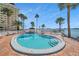A luxurious outdoor swimming pool overlooks the water with palm trees, and lounge chairs at 4775 Cove Cir # 205, St Petersburg, FL 33708