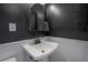 A pedestal sink is set against a black textured wall with a white tile backsplash in this cozy bathroom at 5502 N 9Th St, Tampa, FL 33604