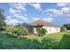 View of the backyard with lush green grass, garden, screened lanai and neutral-colored single-story home under a blue sky at 6214 45Th E Ln, Bradenton, FL 34203