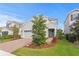 Beautiful two-story home with gray siding, brick driveway, blue door, and manicured front yard at 6219 Voyagers Pl, Apollo Beach, FL 33572