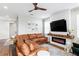 Inviting living room featuring a leather couch, stylish fireplace, and unique ceiling fan at 6219 Voyagers Pl, Apollo Beach, FL 33572