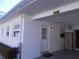 Exterior view of a well-maintained property featuring a covered parking area, a side entrance, and fresh landscaping at 7729 39Th N Ter, St Petersburg, FL 33709
