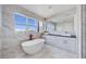 Elegant primary bathroom featuring a freestanding tub, marble walls, and a sleek vanity at 774 Gran Kaymen Way, Apollo Beach, FL 33572