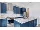 Kitchen boasts blue cabinets, stainless appliances, marble countertops, an island, and a view at 774 Gran Kaymen Way, Apollo Beach, FL 33572