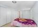 Bedroom with neutral tile floors, closet, one small window, and simple bed frame at 9040 Lunar Ln, Port Richey, FL 34668