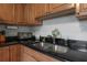 Close-up of the kitchen sink area with black countertops and wooden cabinets at 1053 56Th N Ave, St Petersburg, FL 33703