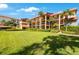 Exterior view of the building with balconies, tropical landscaping, and lush green lawn at 1060 Pinellas Bayway S # 103, St Petersburg, FL 33715