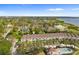 Aerial view of townhome community showcasing lush landscaping, a pool, and proximity to the water at 112 Brent Cir, Oldsmar, FL 34677