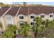 Multi-story condo featuring a brown roof, yellow paint, palm trees, and a two-car garage at 112 Brent Cir, Oldsmar, FL 34677