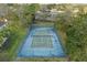 Overhead view of a well-maintained community tennis court surrounded by mature trees and lush green grass at 112 Brent Cir, Oldsmar, FL 34677