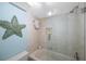 Clean bathroom with a glass-enclosed shower and tub combination, and a starfish wall decoration at 1125 Pinellas Bayway S # 305, St Petersburg, FL 33715