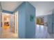 Hallway with blue walls, leading to the living room and a bedroom, with white wood-look floors at 1125 Pinellas Bayway S # 305, St Petersburg, FL 33715