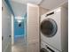 Convenient laundry area with a stacked washer and dryer, and a blue-walled hallway at 1125 Pinellas Bayway S # 305, St Petersburg, FL 33715