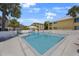 Community pool surrounded by a white fence, lush palms, and buildings on a bright day at 1125 Pinellas Bayway S # 305, St Petersburg, FL 33715