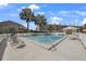 Community pool with deck chairs, palm trees, and privacy fence at 1125 Pinellas Bayway S # 305, St Petersburg, FL 33715