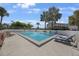 Community pool with deck chairs, palm trees, and privacy fence at 1125 Pinellas Bayway S # 305, St Petersburg, FL 33715