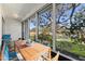 This staged screened porch features a wooden table and chairs, overlooking a pond at 11410 Carriage Hill Dr # 3, Port Richey, FL 34668