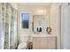 Well-lit bathroom featuring sink with cabinet, toilet, mirror, lighting, and a window at 13855 Rudi Loop, Spring Hill, FL 34609