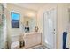 Bright bathroom features a sink with cabinet, toilet, mirror, lighting and a glass door at 13855 Rudi Loop, Spring Hill, FL 34609