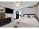 Comfortable bedroom featuring ceiling fan, television, black dresser, and a bed with floral comforter at 13855 Rudi Loop, Spring Hill, FL 34609