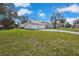 Lush lawn surrounding a three-car garage and home with mature trees at 13855 Rudi Loop, Spring Hill, FL 34609