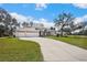 A well-maintained home boasts a three-car garage and a long driveway, set on a lush green lawn at 13855 Rudi Loop, Spring Hill, FL 34609