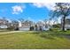 Exterior view of a home with a spacious lawn, a three-car garage, and a beautiful blue front door at 13855 Rudi Loop, Spring Hill, FL 34609