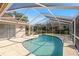 Screened-in pool with a view of the lake surrounded by trees and a blue sky at 14917 Barby Ave, Tampa, FL 33625