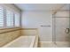 Main bathroom with a tub, glass shower, and bright, sunny window at 15901 Benton Ct, Tampa, FL 33647