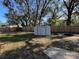 Large, fenced backyard featuring a storage shed and a cozy fire pit area with a brick surround at 1919 E Noel St, Tampa, FL 33610