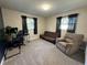 Bedroom featuring neutral walls, carpeted floor, two windows with dark curtains, futon, desk, and comfortable recliner at 1919 E Noel St, Tampa, FL 33610