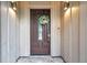 Close-up of the wooden front door with a glass window, a seasonal wreath, and two sconce lights at 2151 E Leewynn Dr, Sarasota, FL 34240