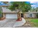 Two story home featuring a stone facade, a two car garage, manicured lawn, and a mature tree at 2151 E Leewynn Dr, Sarasota, FL 34240