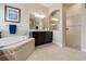 Elegant bathroom featuring a soaking tub, dark wood cabinets, dual sinks, and a glass shower at 21537 Draycott Way, Land O Lakes, FL 34637