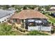 Aerial view of the backyard with a screen enclosed lanai with an umbrella table and mature landscaping at 2359 Emerald Lake Dr, Sun City Center, FL 33573