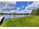 Beautiful lake view from a grassy lawn, featuring a dock and surrounding trees at 3046 Lake Padgett Dr, Land O Lakes, FL 34639