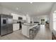 Open-concept kitchen featuring stainless steel appliances, a granite countertop island with barstool seating, and seamless flow to living area at 3664 Zephyr Preserve Pl, Zephyrhills, FL 33541