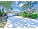 Home exterior featuring a driveway, a front-facing garage, and mature landscaping including a tall palm tree at 4606 W Oakellar Ave, Tampa, FL 33611