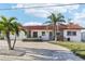 Inviting single-story home with a red tile roof and a brick driveway, enhanced by mature palm trees at 619 59Th Ave, St Pete Beach, FL 33706