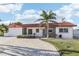 Inviting single-story home with a red tile roof and a brick driveway, enhanced by mature palm trees at 619 59Th Ave, St Pete Beach, FL 33706