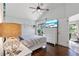 Bright bedroom with wood floors, a ceiling fan, and a large flat-screen television at 692 Greenglen Ln, Palm Harbor, FL 34684