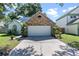 Front view of the 2-car garage with brick facade and driveway framed by greenery at 692 Greenglen Ln, Palm Harbor, FL 34684